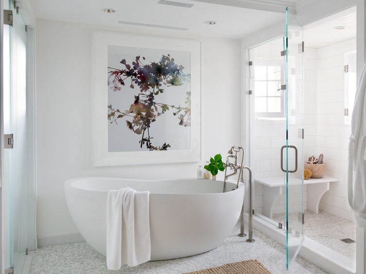 دکوراسیون حمام زیبا و شیک با دیوارها و وان سفید و اتاق دوش شیشه ای که تابلو با طرح شاخه درختان دارد